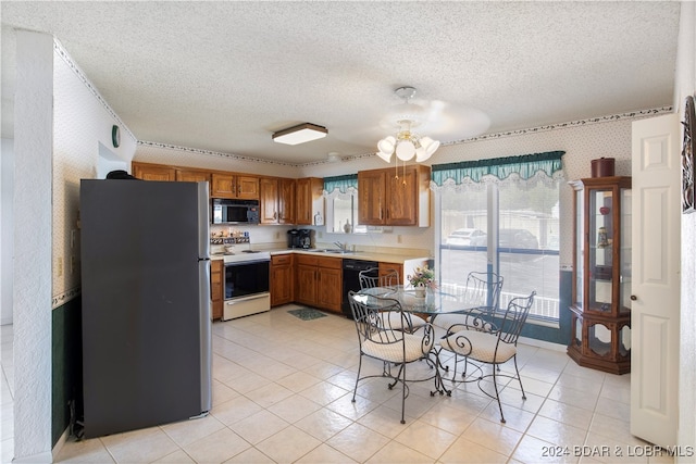 kitchen with black appliances, light tile patterned floors, sink, and a textured ceiling