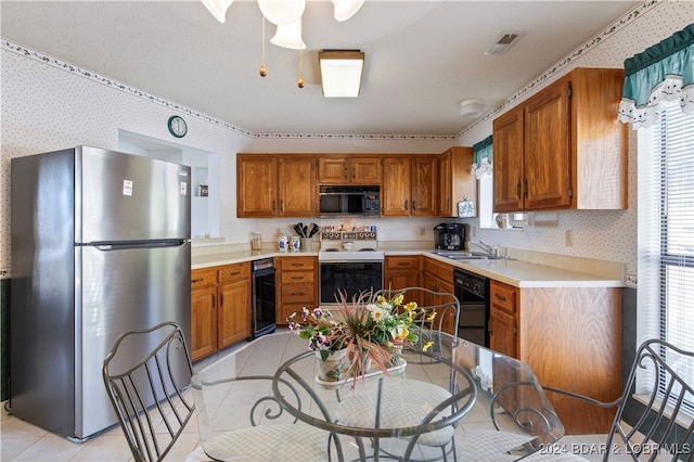 kitchen with black appliances, light tile patterned flooring, sink, and beverage cooler