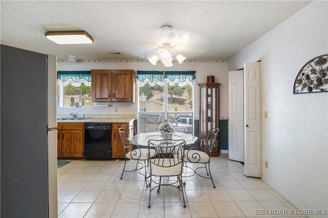 dining space featuring sink, light tile patterned floors, and a textured ceiling