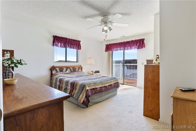 bedroom featuring access to exterior, carpet flooring, a textured ceiling, ceiling fan, and a water view