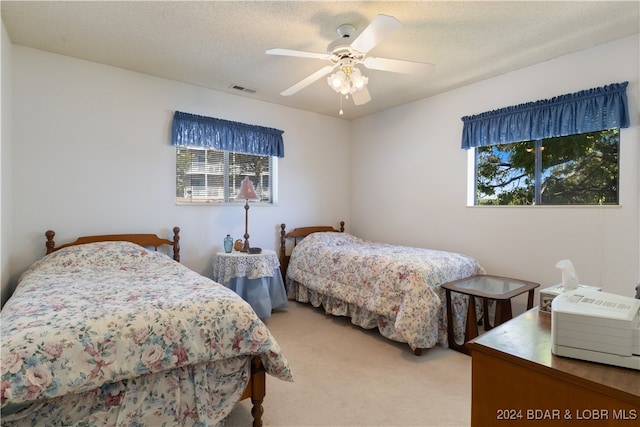 carpeted bedroom with ceiling fan and a textured ceiling