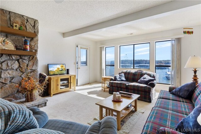 775 Winn Rd Unit 4I, Osage Beach, MO 65065 - living room featuring beamed ceiling, light colored carpet, a textured ceiling, healthy amount of natural light, and a stone fireplace