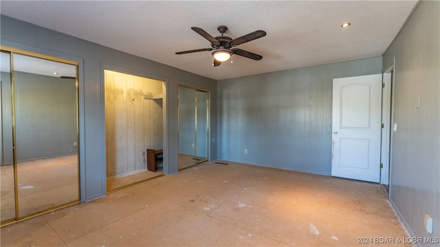 unfurnished bedroom featuring a textured ceiling, multiple closets, and ceiling fan