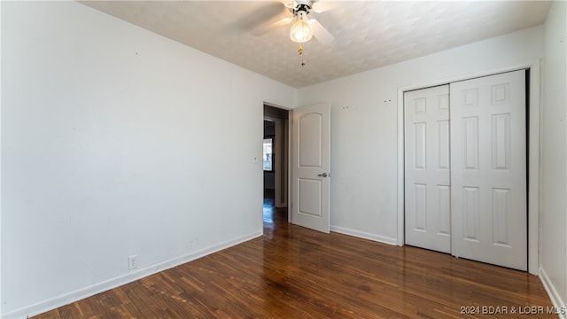 unfurnished bedroom with ceiling fan, a closet, and dark hardwood / wood-style flooring