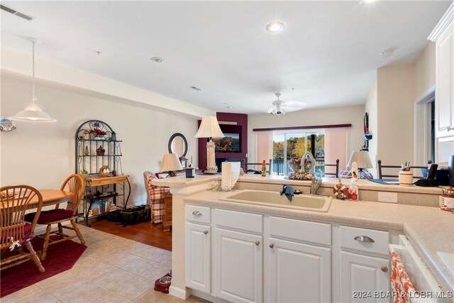 kitchen featuring light tile patterned flooring, sink, hanging light fixtures, white cabinetry, and ceiling fan