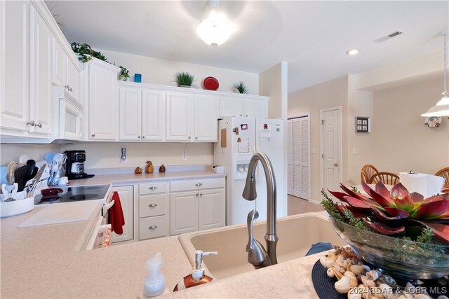 kitchen featuring white appliances, white cabinetry, sink, and pendant lighting