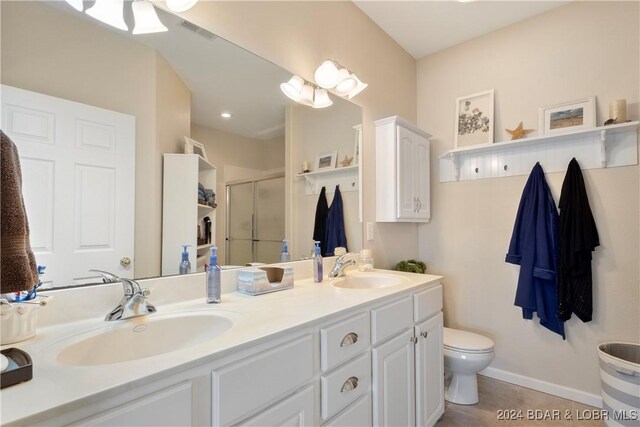 bathroom with toilet, vanity, tile patterned floors, and a shower with door