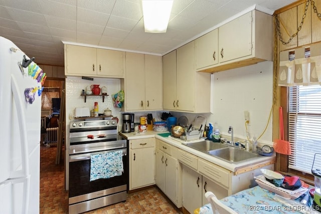 kitchen featuring sink, white fridge, cream cabinetry, and stainless steel electric range oven