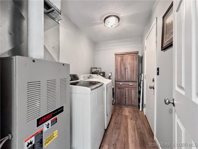 clothes washing area with a textured ceiling, light wood-type flooring, and washing machine and clothes dryer