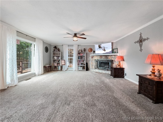 carpeted living room featuring a stone fireplace, ornamental molding, a textured ceiling, and ceiling fan