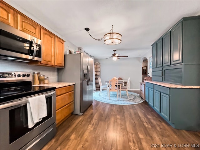 kitchen featuring dark wood-type flooring, ceiling fan, tasteful backsplash, and appliances with stainless steel finishes