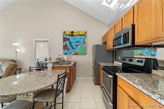 kitchen featuring light tile patterned floors, a breakfast bar, light stone countertops, sink, and stainless steel appliances