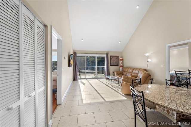 living room with high vaulted ceiling and light tile patterned floors