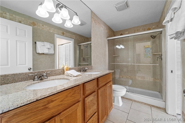 bathroom with a textured ceiling, toilet, vanity, an enclosed shower, and tile patterned floors