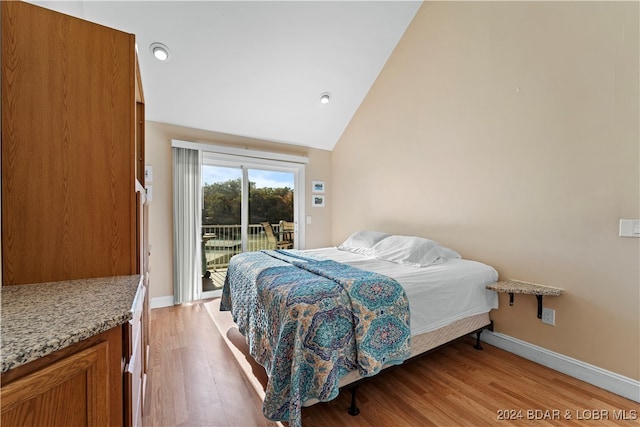 bedroom with light hardwood / wood-style floors, vaulted ceiling, and access to exterior