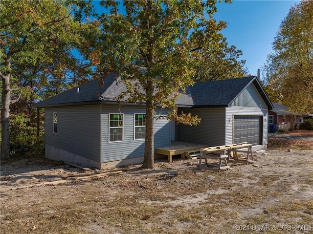 exterior space featuring an attached garage and roof with shingles