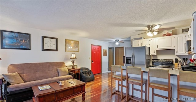 living room with hardwood / wood-style floors, ceiling fan, and a textured ceiling