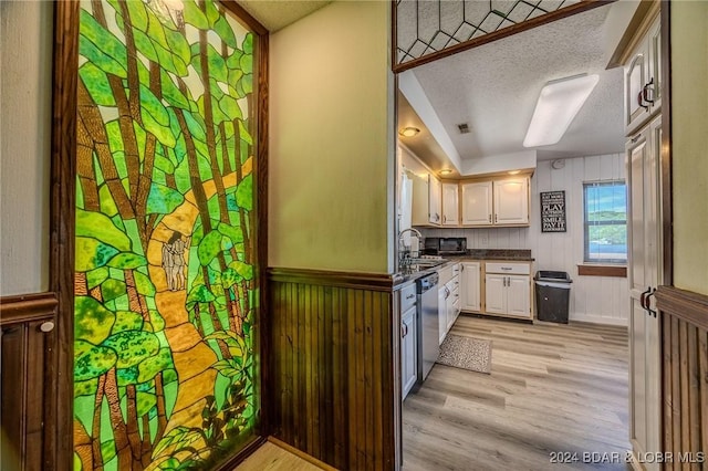 kitchen with dishwasher, a textured ceiling, white cabinetry, and light hardwood / wood-style flooring