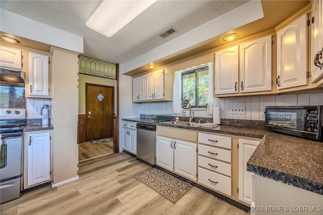 kitchen with dark countertops, light wood-style floors, visible vents, and stainless steel appliances