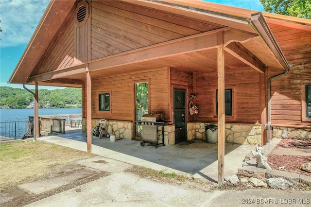 view of patio / terrace with a water view, an outbuilding, area for grilling, and an exterior structure