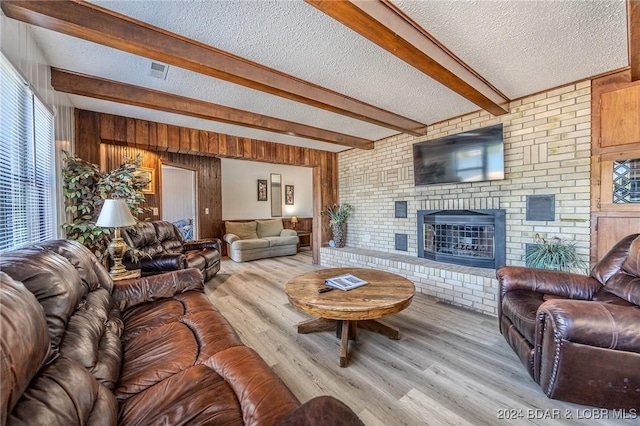 living room with beamed ceiling, a textured ceiling, and light hardwood / wood-style flooring