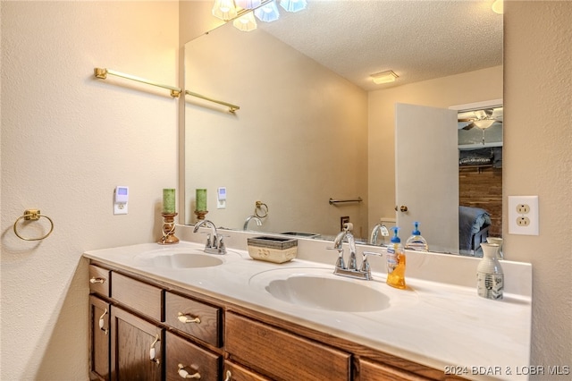 bathroom featuring vanity, ceiling fan, and a textured ceiling