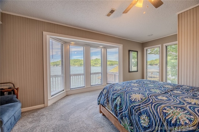 carpeted bedroom with ceiling fan, ornamental molding, and a textured ceiling