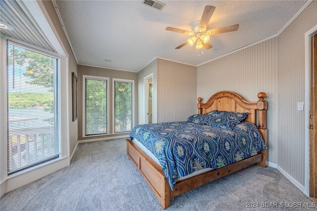 bedroom featuring ceiling fan, crown molding, carpet floors, and a textured ceiling