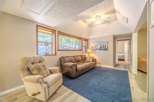 living room with ceiling fan, light hardwood / wood-style floors, lofted ceiling, and a textured ceiling