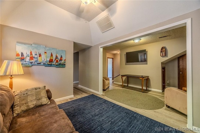 interior space featuring ceiling fan, light hardwood / wood-style floors, a textured ceiling, and vaulted ceiling