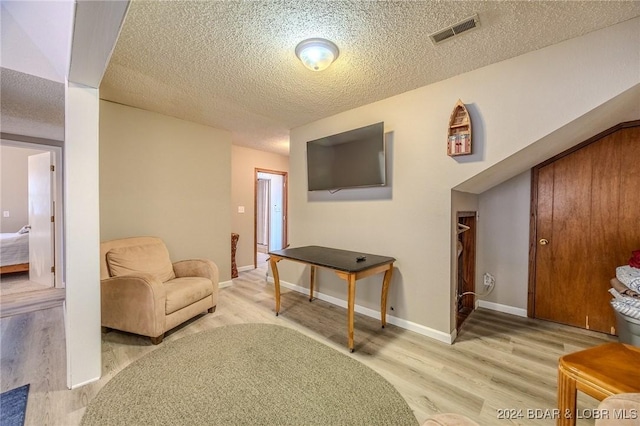 sitting room with a textured ceiling, wood finished floors, and visible vents