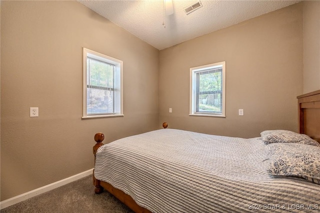 carpeted bedroom featuring a textured ceiling, visible vents, and baseboards