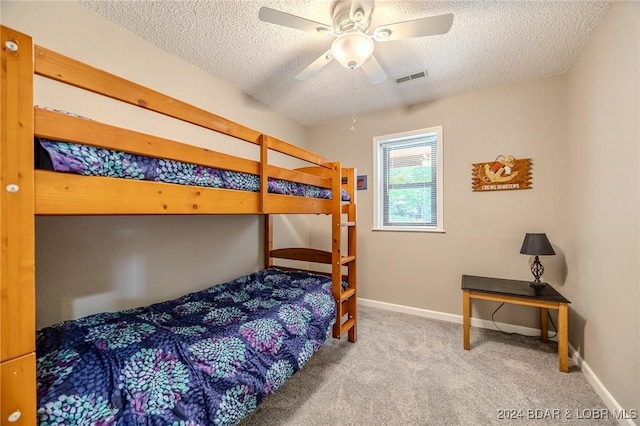 carpeted bedroom with ceiling fan and a textured ceiling