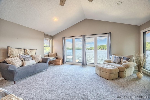 interior space featuring lofted ceiling, a water view, carpet flooring, ceiling fan, and a textured ceiling