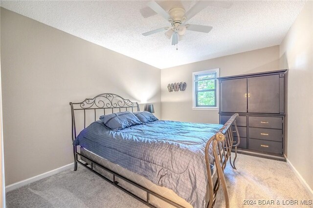 carpeted bedroom featuring ceiling fan and a textured ceiling