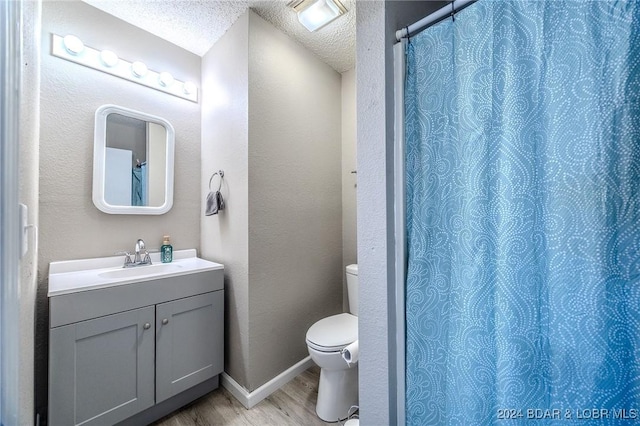 bathroom with vanity, a textured ceiling, hardwood / wood-style flooring, toilet, and curtained shower