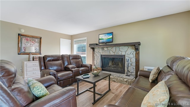 living room featuring a stone fireplace and light wood-type flooring