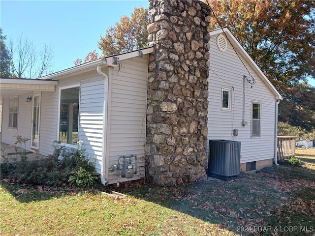 607 N Hughes Ave, Stover, MO 65078 - view of side of property with central air condition unit, a chimney, and a yard
