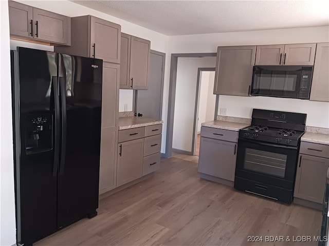 kitchen with black appliances, gray cabinetry, and light wood-type flooring