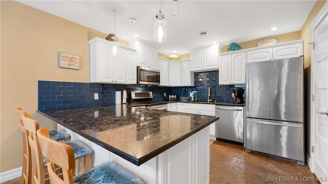 kitchen featuring a breakfast bar, white cabinetry, sink, decorative light fixtures, and stainless steel appliances