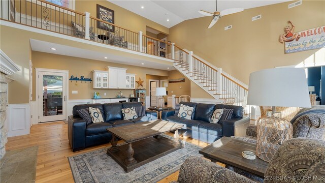 living room with light hardwood / wood-style flooring, high vaulted ceiling, and ceiling fan