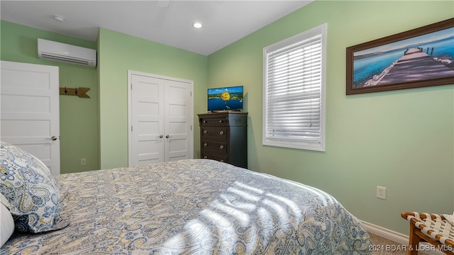 bedroom with an AC wall unit, carpet floors, and a closet