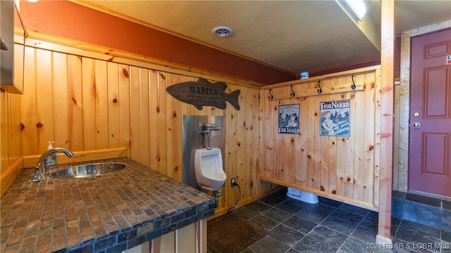 bathroom featuring ornamental molding, sink, toilet, and wooden walls