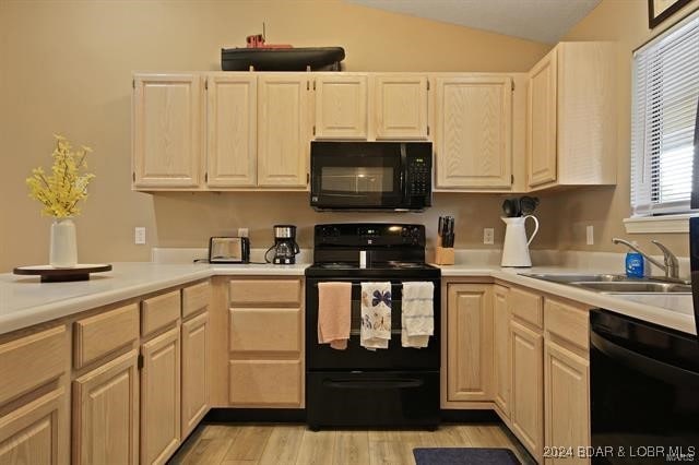 kitchen featuring light brown cabinets, vaulted ceiling, light hardwood / wood-style flooring, black appliances, and sink