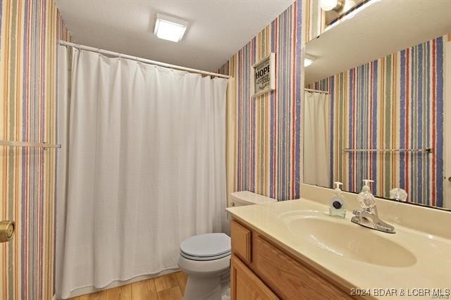 611 Lazy Days Rd Unit X11, Osage Beach, MO 65065 - full bathroom featuring vanity, toilet, wallpapered walls, wood finished floors, and a shower with curtain