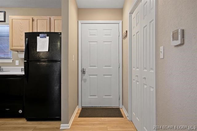 kitchen with light brown cabinetry, black appliances, and light hardwood / wood-style flooring