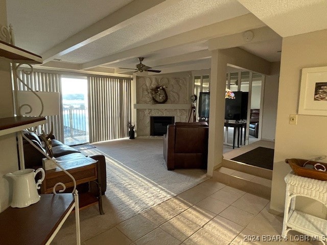 living room with ceiling fan, a textured ceiling, beamed ceiling, and light tile patterned floors