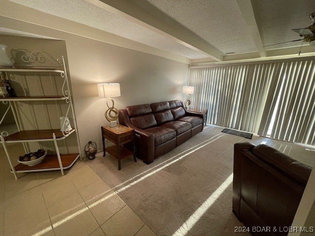 tiled living room with beam ceiling, a textured ceiling, and ceiling fan