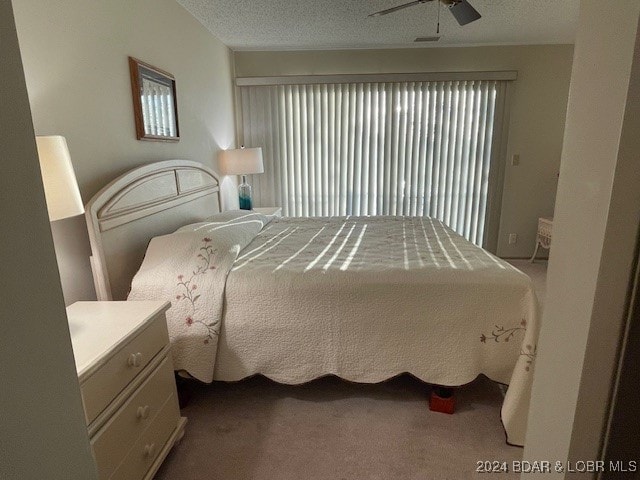 bedroom with ceiling fan, carpet flooring, and a textured ceiling