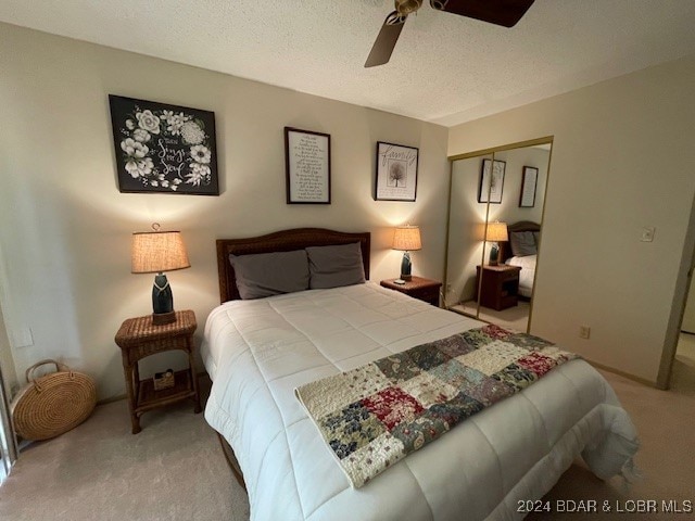 carpeted bedroom with a closet, a textured ceiling, and ceiling fan